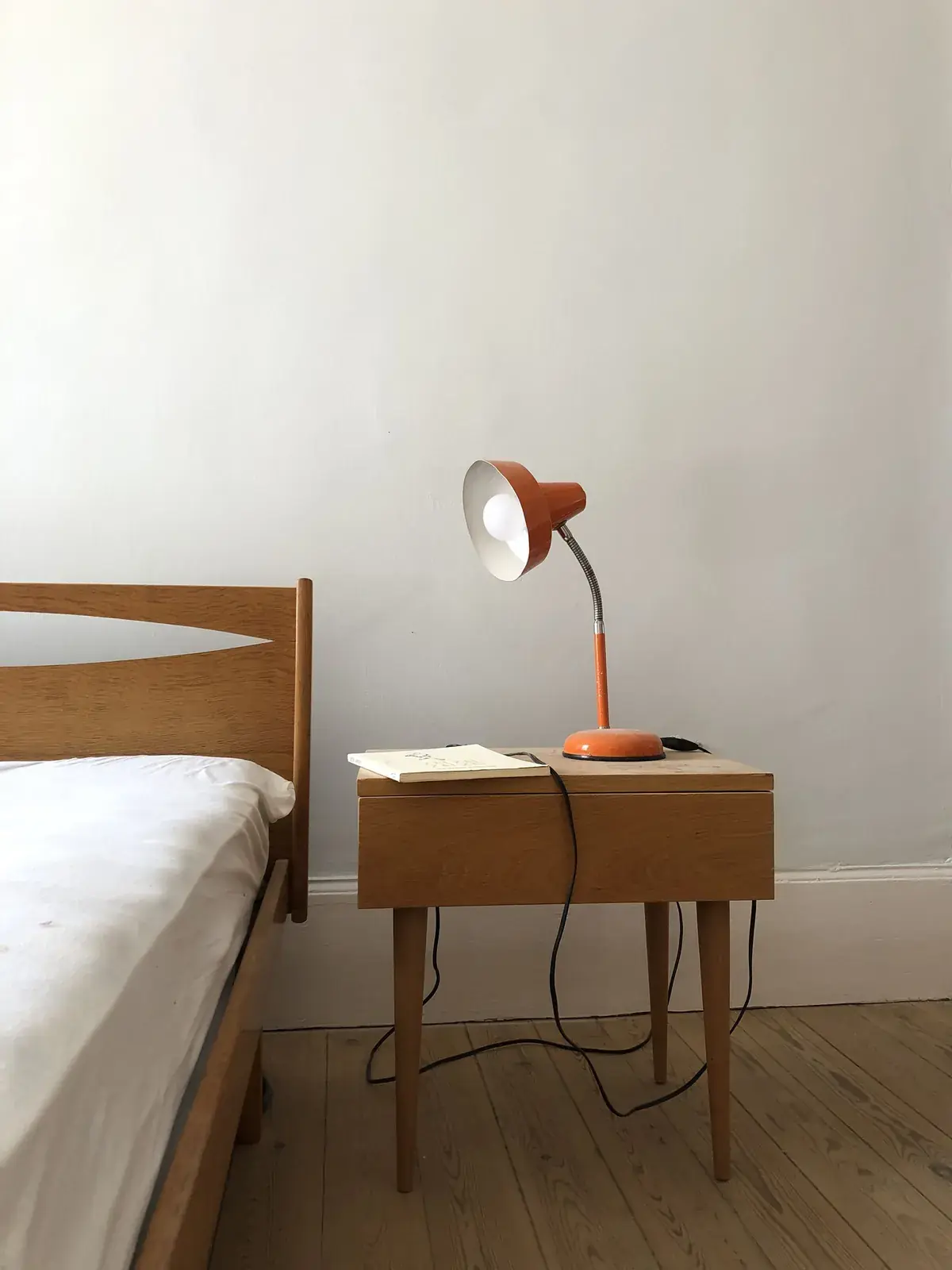 Chambre lumineuse avec lit en bois et lampe orange vintage