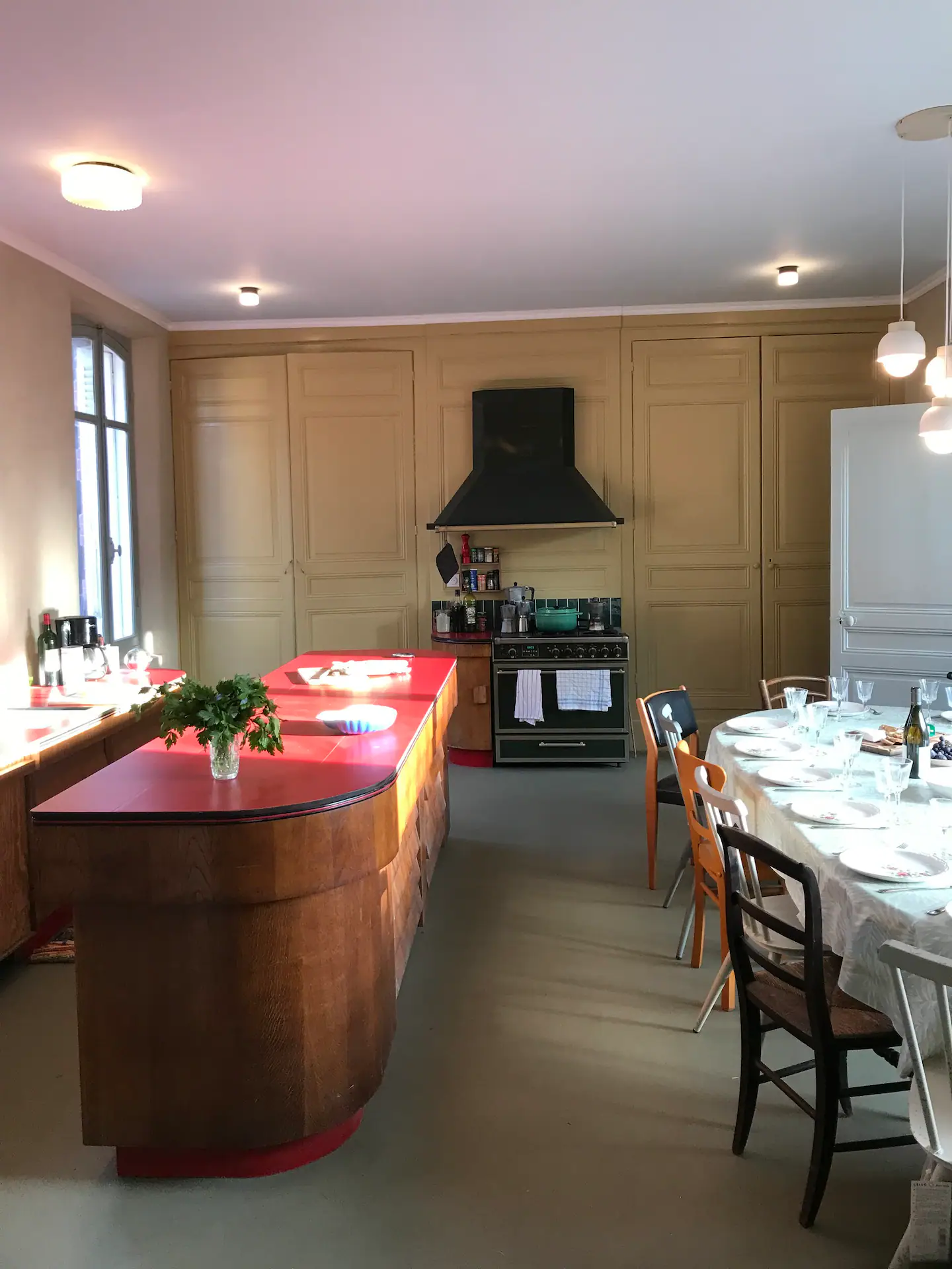 Grande cuisine conviviale avec longue table et îlot central rouge