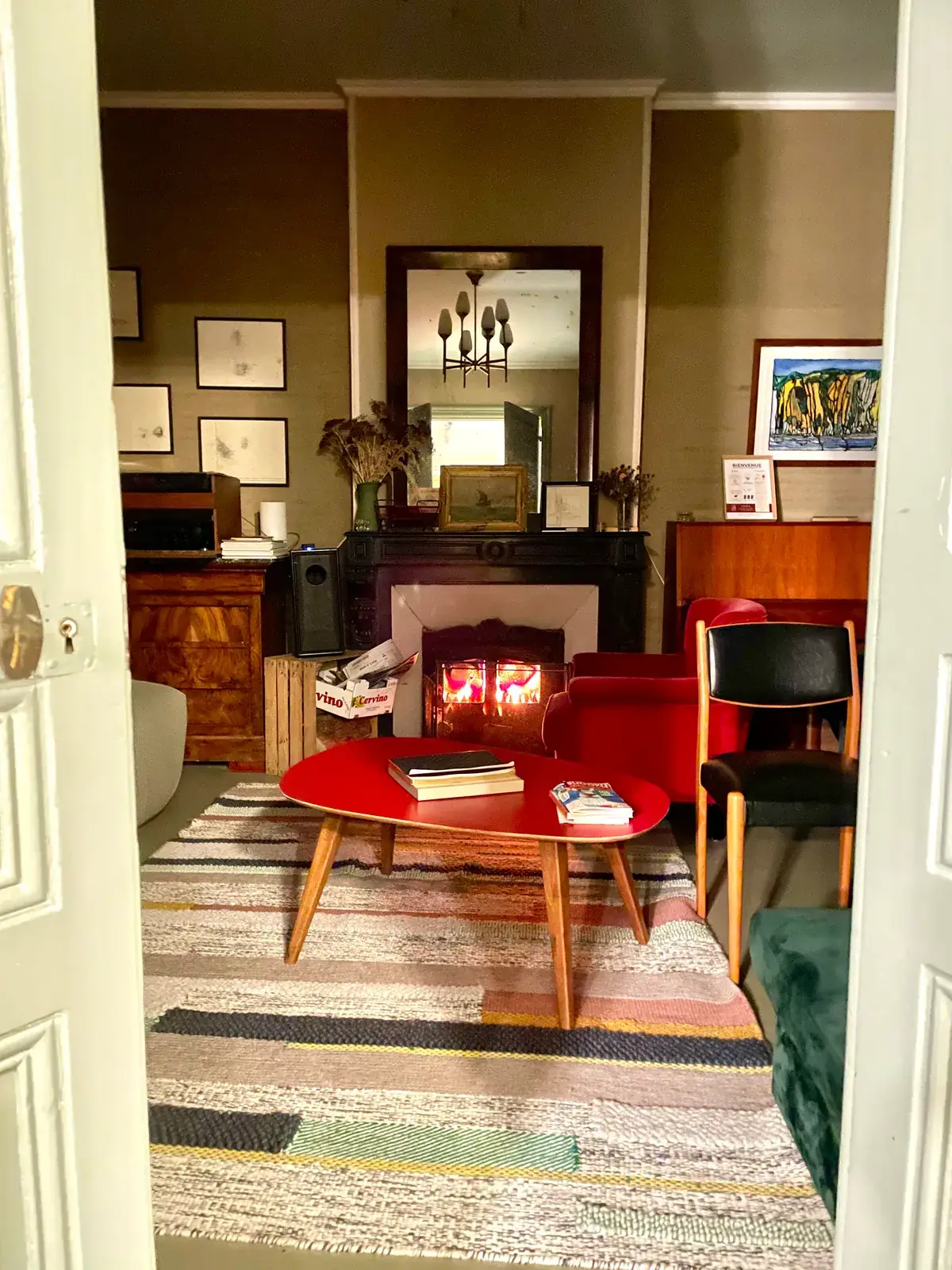 Salon au coin du feu le soir, fauteuils rouges devant la cheminée en marbre noir