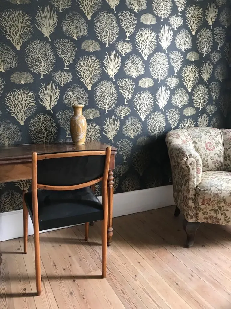 Coin salon avec papier peint floral et fauteuil chiné